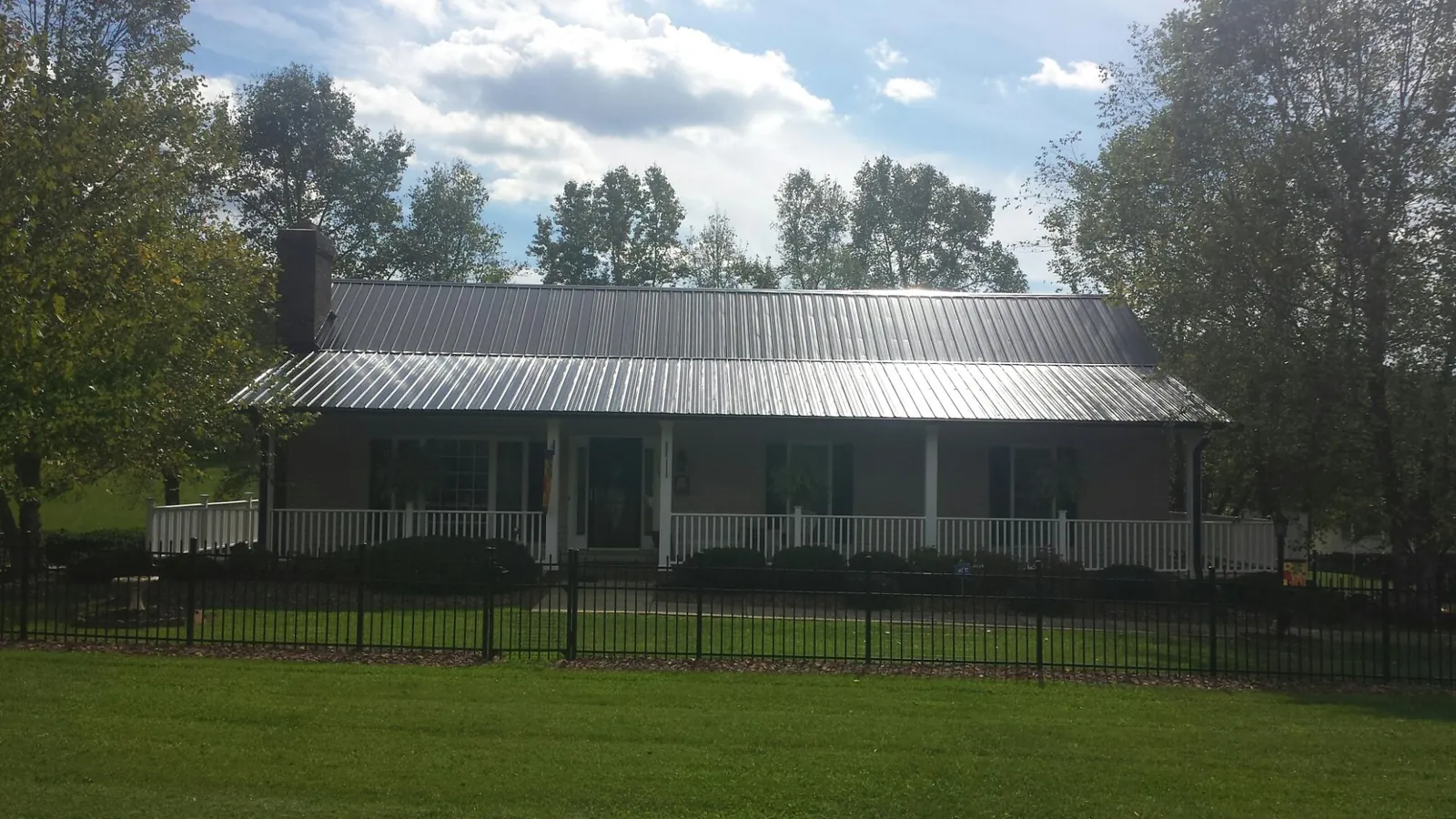 Gray metal roof on a brick ranch with a full width front porch — Gutter Guard Installation work by our crew in Liberty