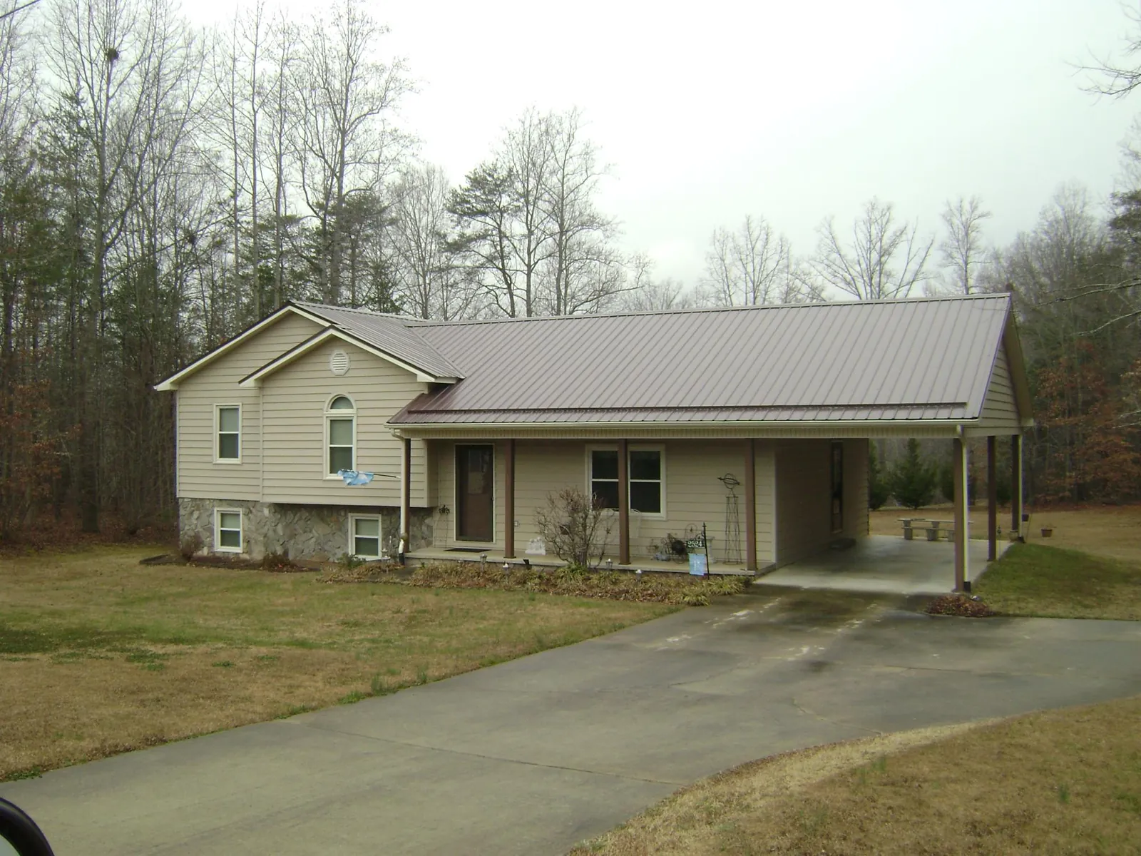 Brown metal roof on a tan split level home with an attached carport in Liberty